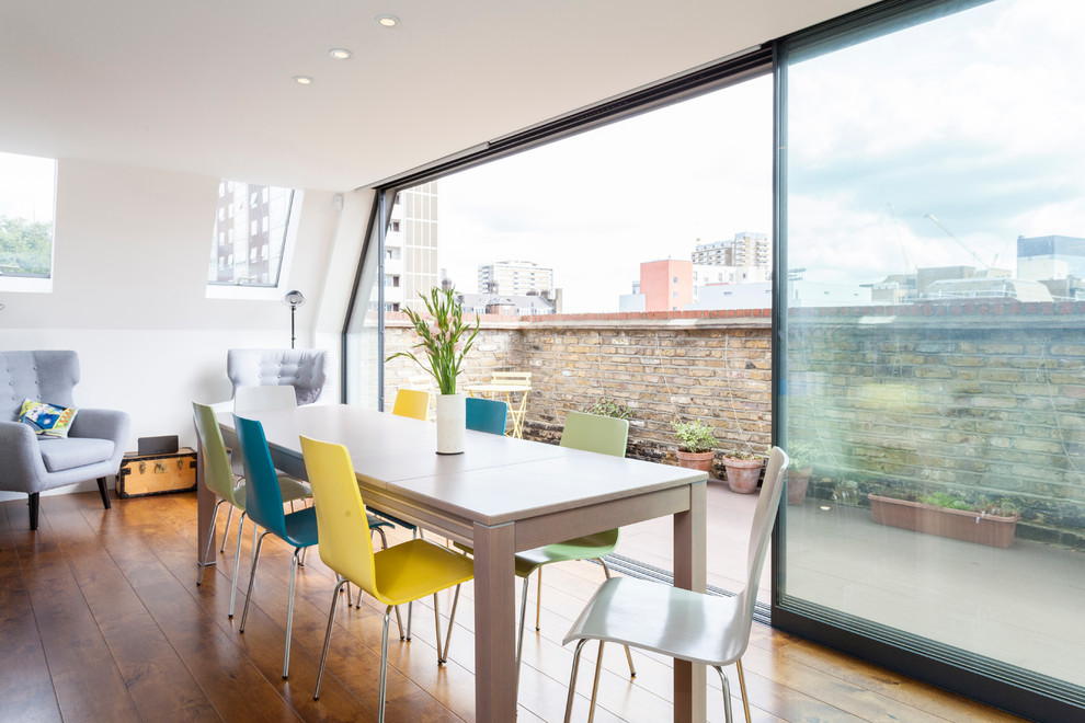 Photo of a small contemporary open plan dining room in London with white walls and medium hardwood flooring.