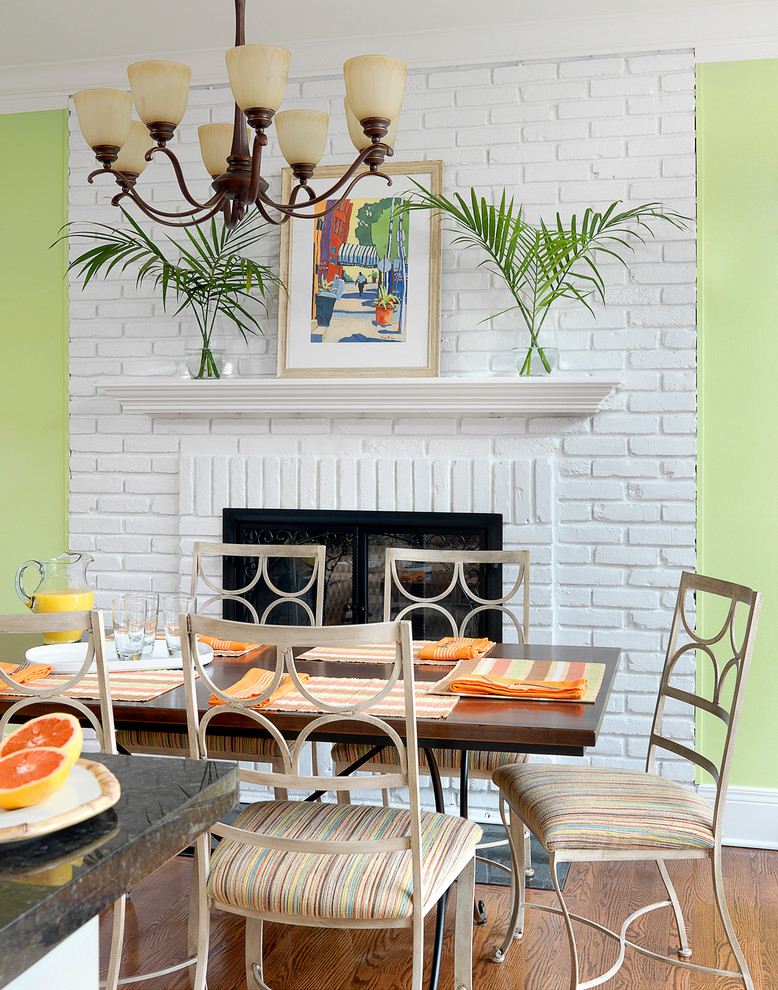 Foto di una grande sala da pranzo aperta verso la cucina stile marinaro con pareti verdi, pavimento in legno massello medio, cornice del camino in mattoni e camino classico