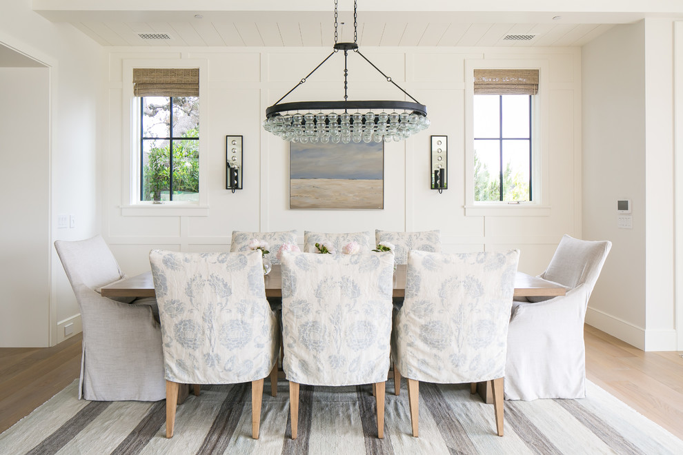 Photo of a coastal dining room in Orange County with white walls, light hardwood flooring and brown floors.