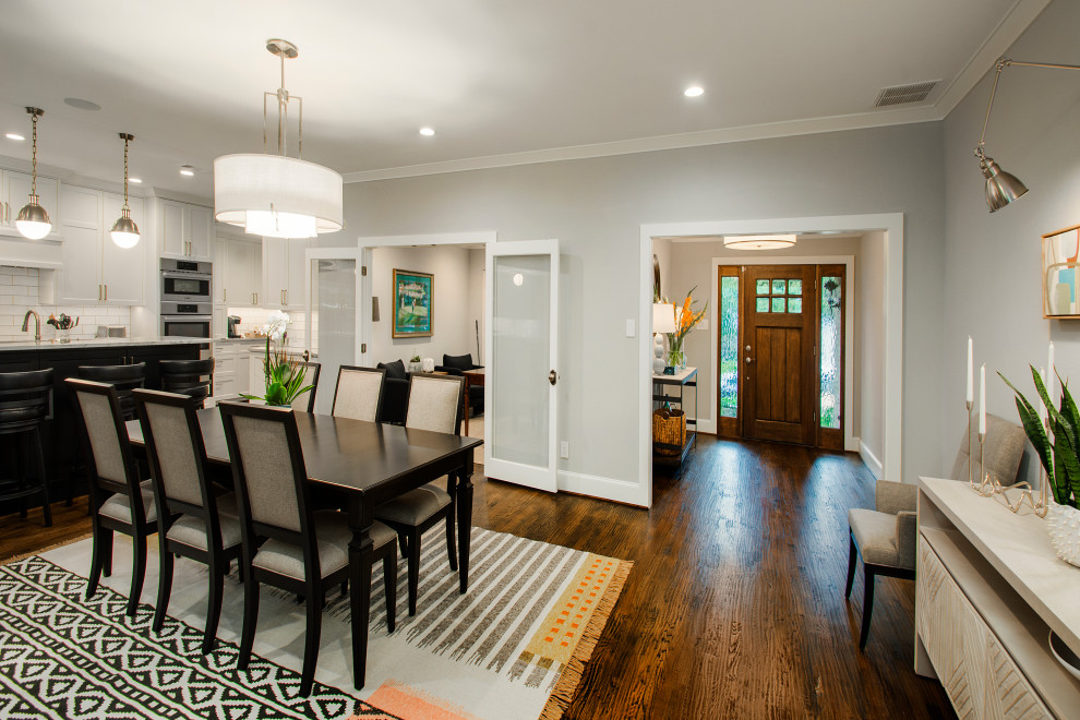 This is an example of a medium sized traditional open plan dining room in Dallas with grey walls, dark hardwood flooring, a two-sided fireplace, a tiled fireplace surround and brown floors.