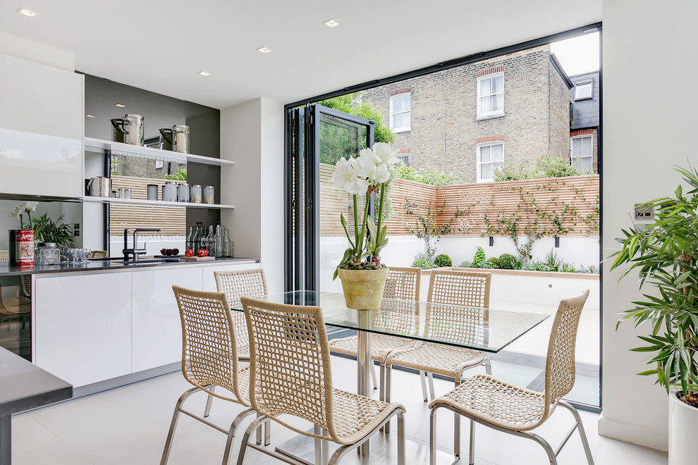 This is an example of a contemporary kitchen/dining room in London with white walls, no fireplace and white floors.