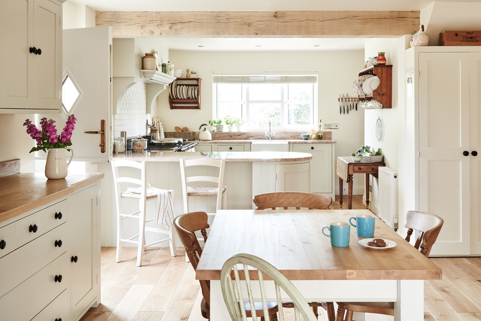 Réalisation d'une salle à manger ouverte sur la cuisine champêtre avec un mur blanc, parquet clair, aucune cheminée et un sol beige.