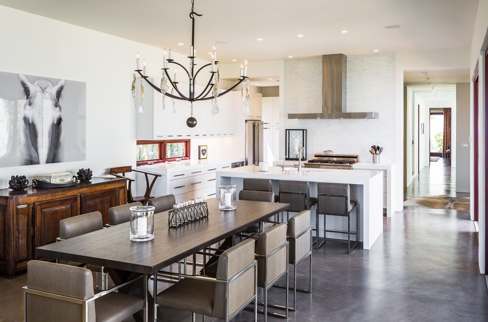 На фото: кухня-столовая в современном стиле с бетонным полом и белыми стенами без камина