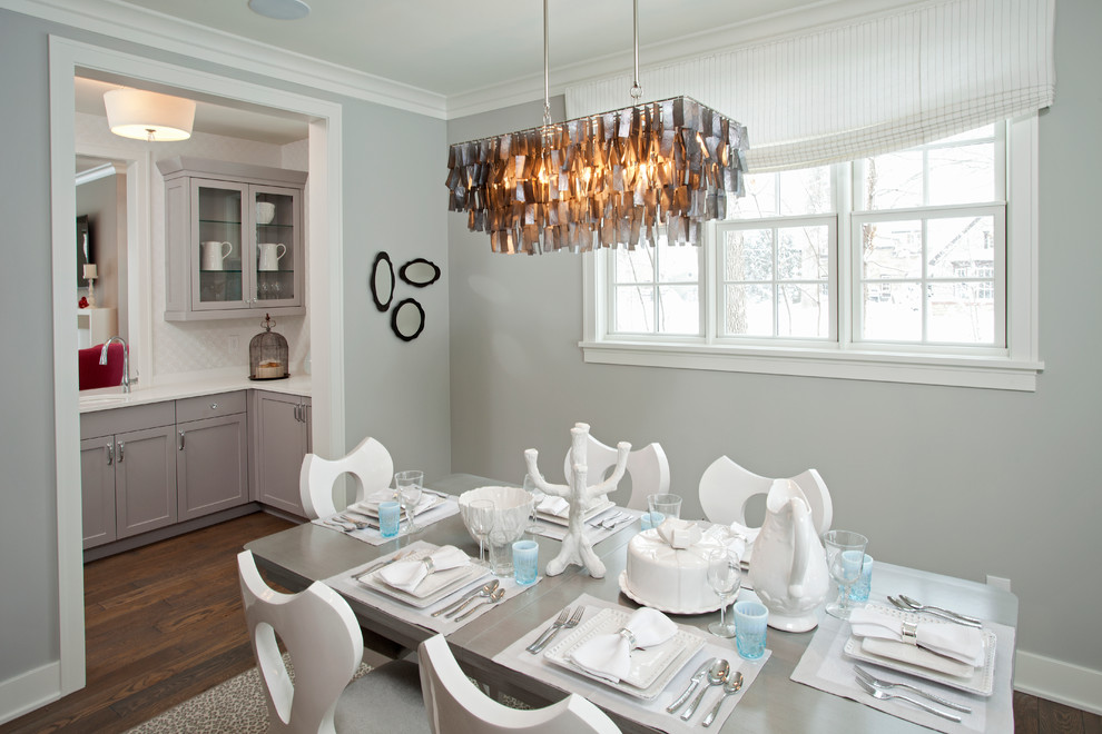Cette photo montre une salle à manger ouverte sur la cuisine bord de mer avec un mur gris et parquet foncé.