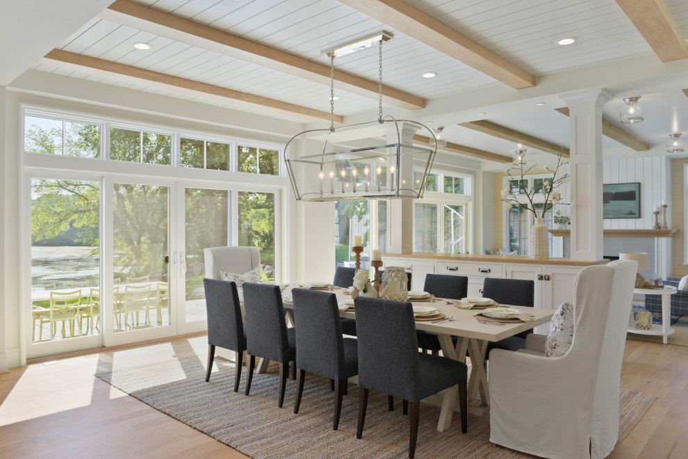Idee per una sala da pranzo aperta verso il soggiorno stile marinaro con pareti bianche, pavimento in legno massello medio e pavimento marrone