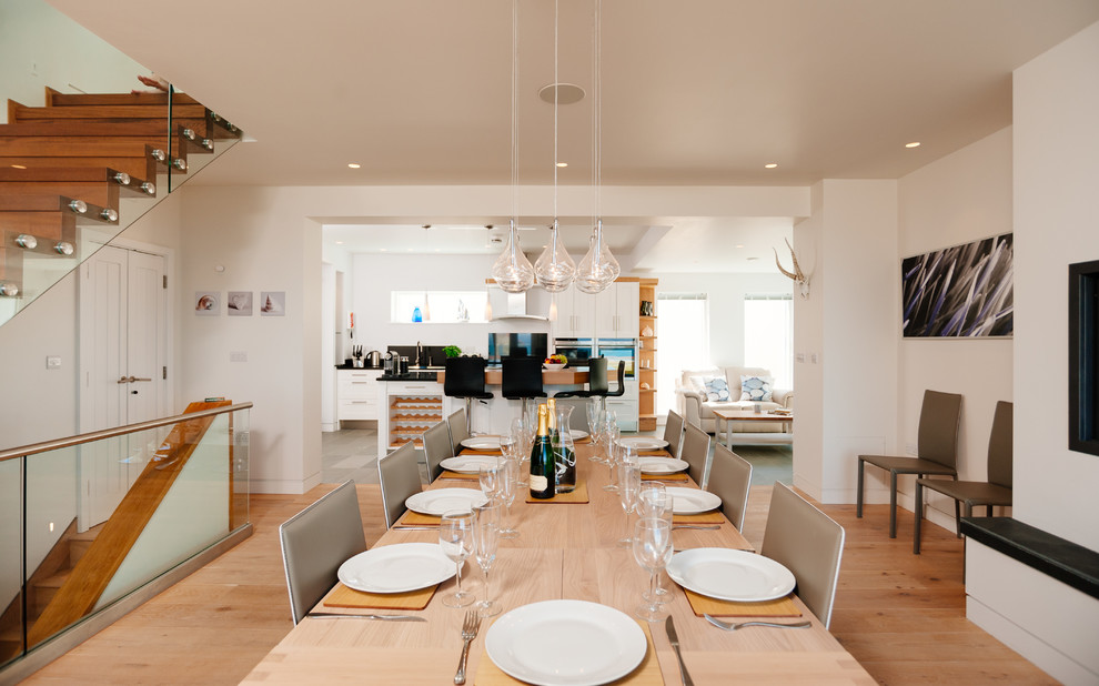 Ispirazione per una sala da pranzo aperta verso il soggiorno costiera con pareti bianche e parquet chiaro