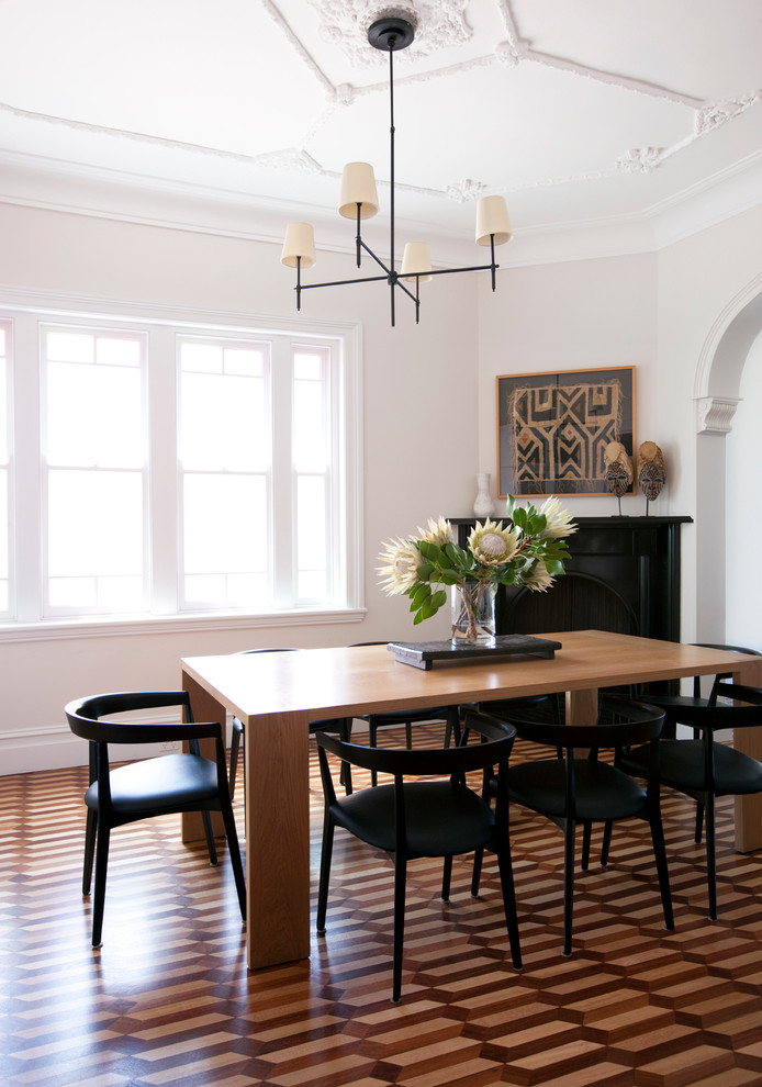 This is an example of a contemporary enclosed dining room in Sydney with white walls and a corner fireplace.