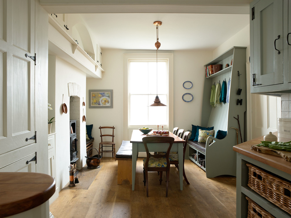 Cette image montre une salle à manger ouverte sur la cuisine marine avec un sol en bois brun, un mur blanc et un poêle à bois.