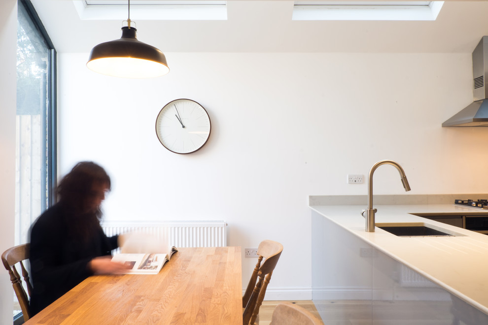 Esempio di una sala da pranzo aperta verso la cucina minimal di medie dimensioni con pareti bianche, parquet chiaro e pavimento marrone