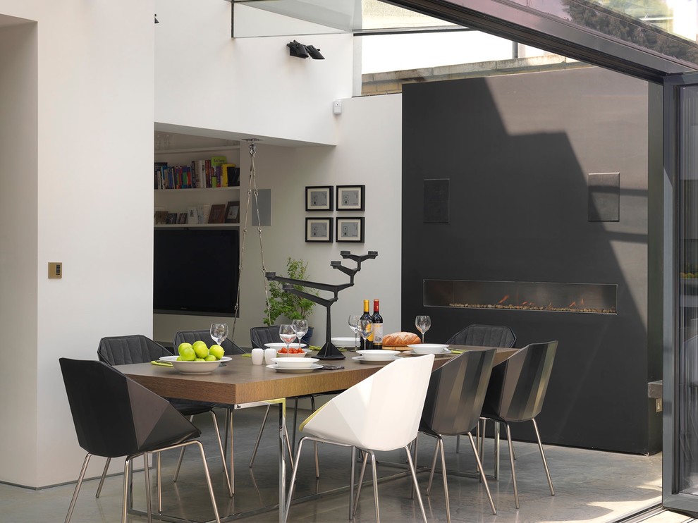 This is an example of a contemporary dining room in London with grey walls and a ribbon fireplace.