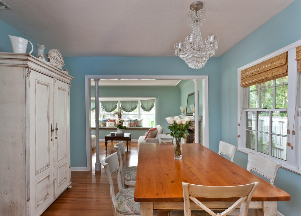 Cette photo montre une salle à manger bord de mer fermée avec un mur bleu, un sol en bois brun et aucune cheminée.