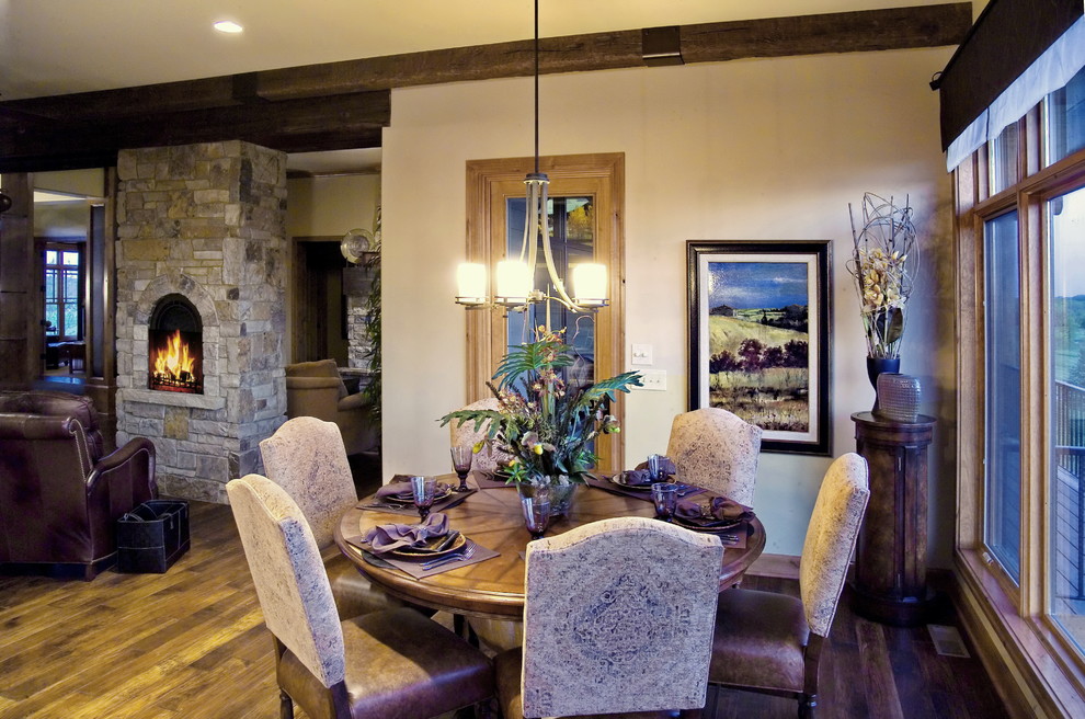 Photo of a medium sized traditional kitchen/dining room in Omaha with beige walls, dark hardwood flooring, a standard fireplace, a stone fireplace surround and brown floors.