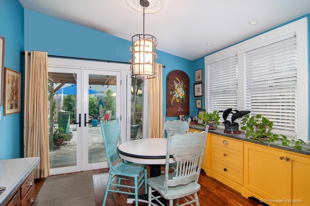 Foto di una piccola sala da pranzo aperta verso la cucina costiera con pareti blu e parquet scuro