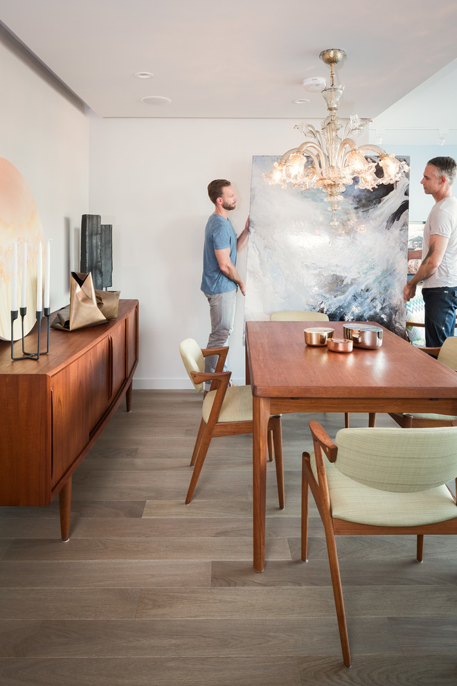 Réalisation d'une salle à manger ouverte sur la cuisine vintage avec un mur blanc et un sol en bois brun.