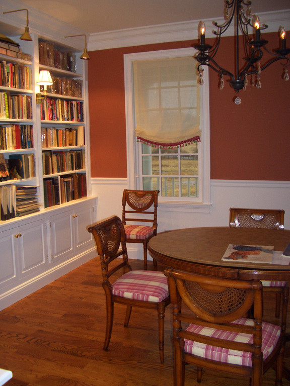 Immagine di una sala da pranzo classica chiusa e di medie dimensioni con pareti rosse, pavimento in legno massello medio e nessun camino