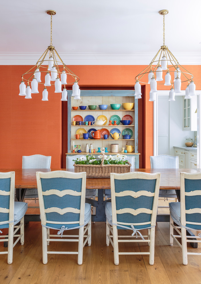 Idée de décoration pour une grande salle à manger ouverte sur le salon champêtre avec un mur orange, parquet clair et un sol marron.