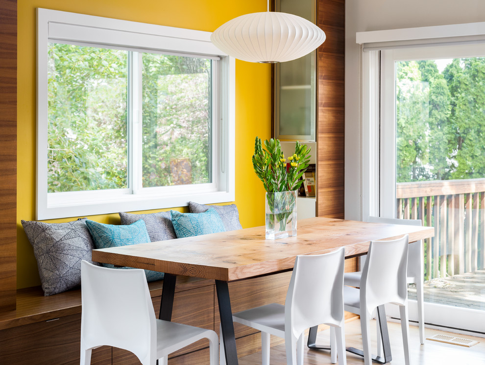 Cette image montre une salle à manger ouverte sur le salon design de taille moyenne avec un mur jaune, parquet clair et aucune cheminée.