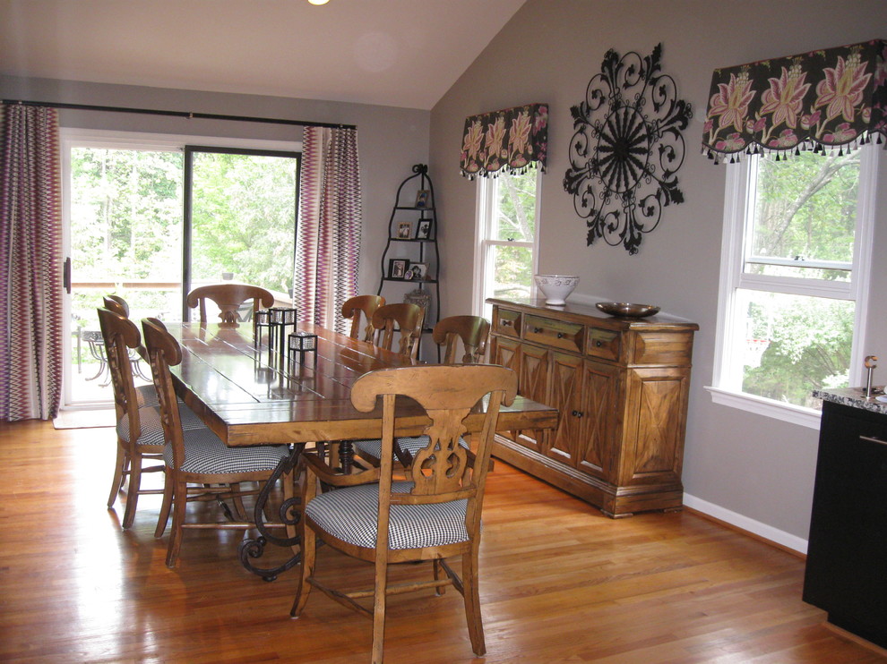 Immagine di una grande sala da pranzo aperta verso la cucina tradizionale con pareti grigie, pavimento in legno massello medio, nessun camino e pavimento marrone