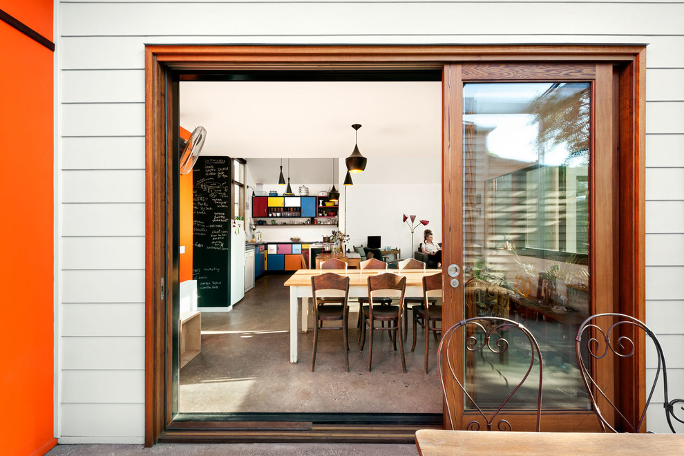 Cette image montre une salle à manger ouverte sur le salon design de taille moyenne avec un mur blanc, sol en béton ciré, aucune cheminée et un sol gris.