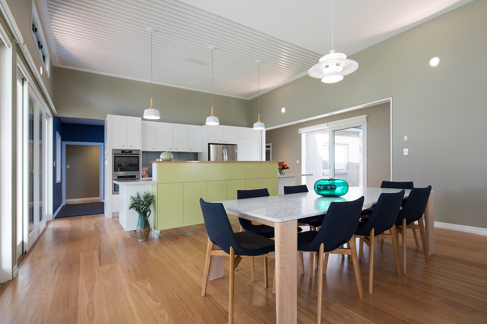 Cette photo montre une salle à manger ouverte sur la cuisine tendance de taille moyenne avec un sol en bois brun et un mur vert.