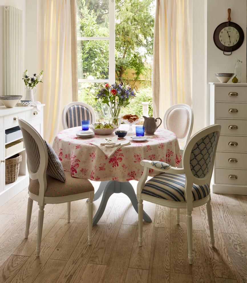Exemple d'une salle à manger ouverte sur la cuisine nature de taille moyenne avec un mur blanc et parquet clair.