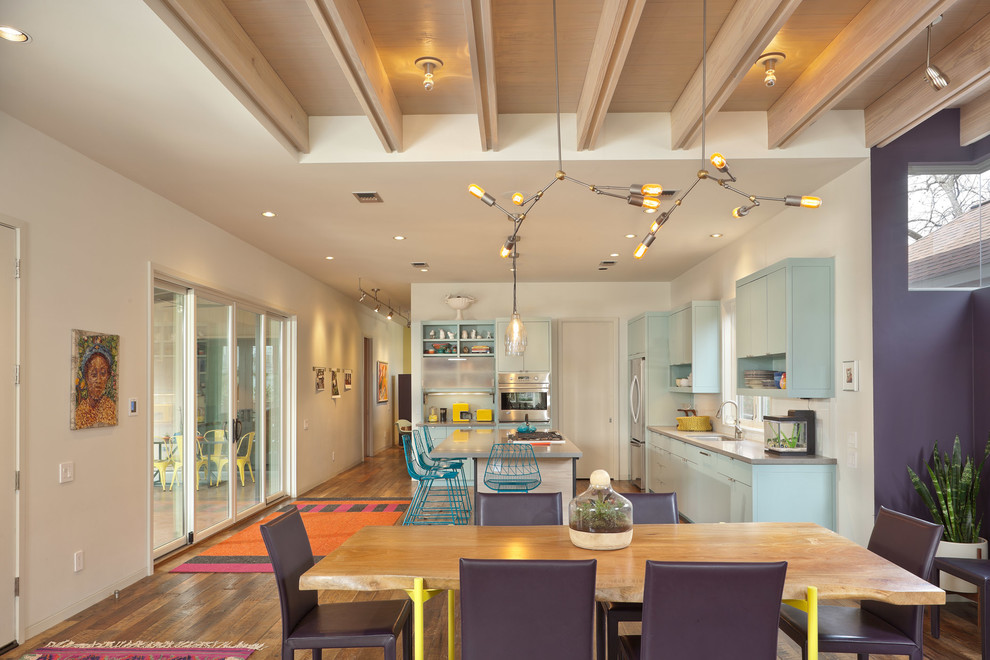 Diseño de comedor actual abierto con paredes púrpuras y suelo de madera en tonos medios