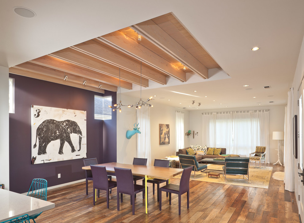 Immagine di una sala da pranzo aperta verso il soggiorno contemporanea con pareti viola e pavimento in legno massello medio
