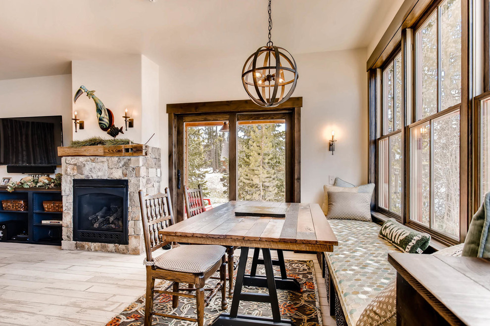 Inspiration for a small rustic open plan dining room in Denver with porcelain flooring, a standard fireplace, a stone fireplace surround and white floors.