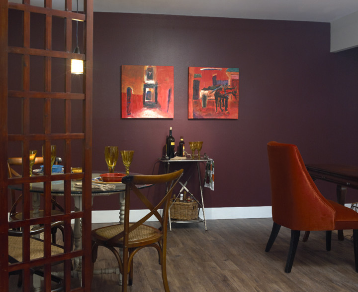 Cette image montre une petite salle à manger ouverte sur le salon bohème avec un mur rouge.