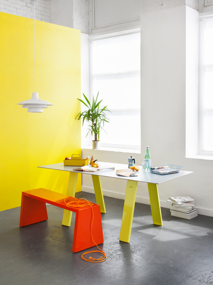 Modernes Esszimmer mit gelber Wandfarbe und Betonboden in London