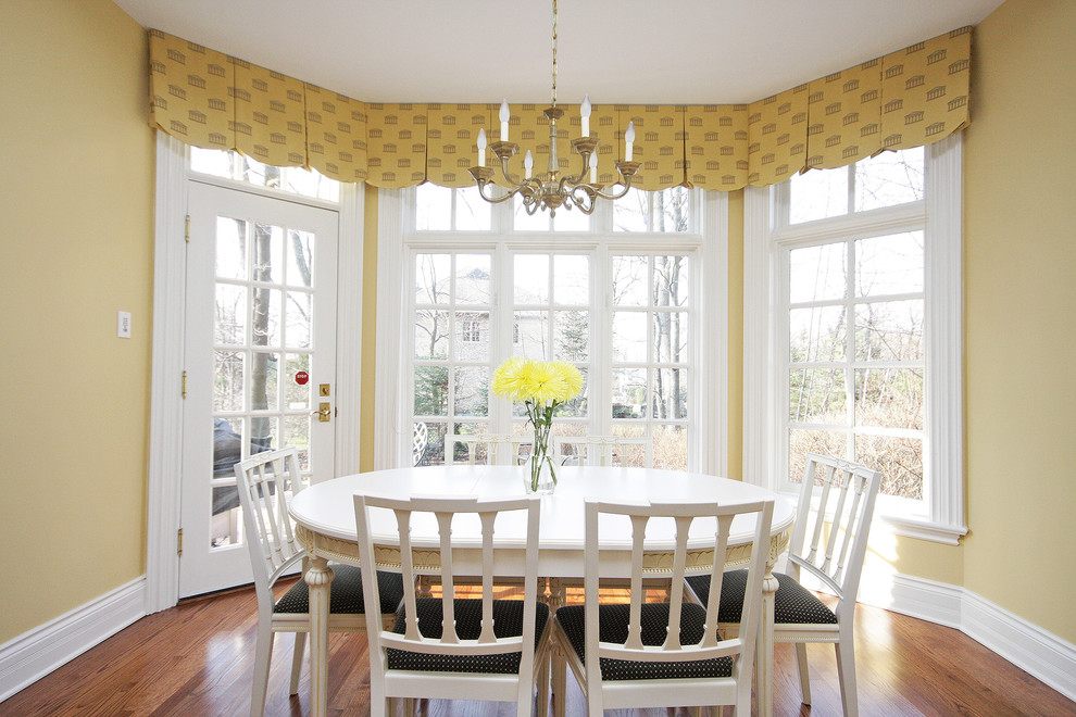 Exemple d'une salle à manger chic fermée et de taille moyenne avec un mur jaune, un sol en bois brun et aucune cheminée.