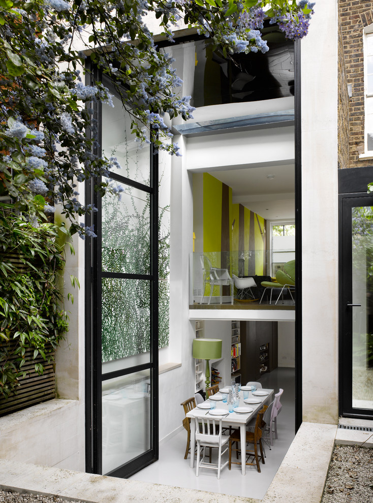 This is an example of a contemporary kitchen/dining room in London with white walls and feature lighting.