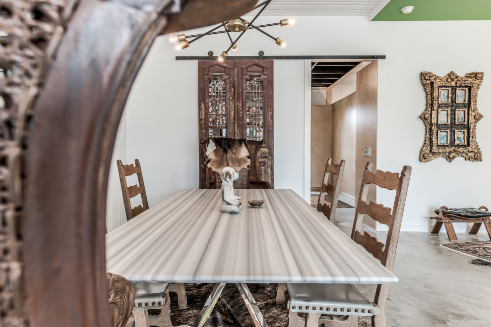 Cette photo montre une petite salle à manger ouverte sur la cuisine chic avec un mur blanc, sol en béton ciré et un sol gris.