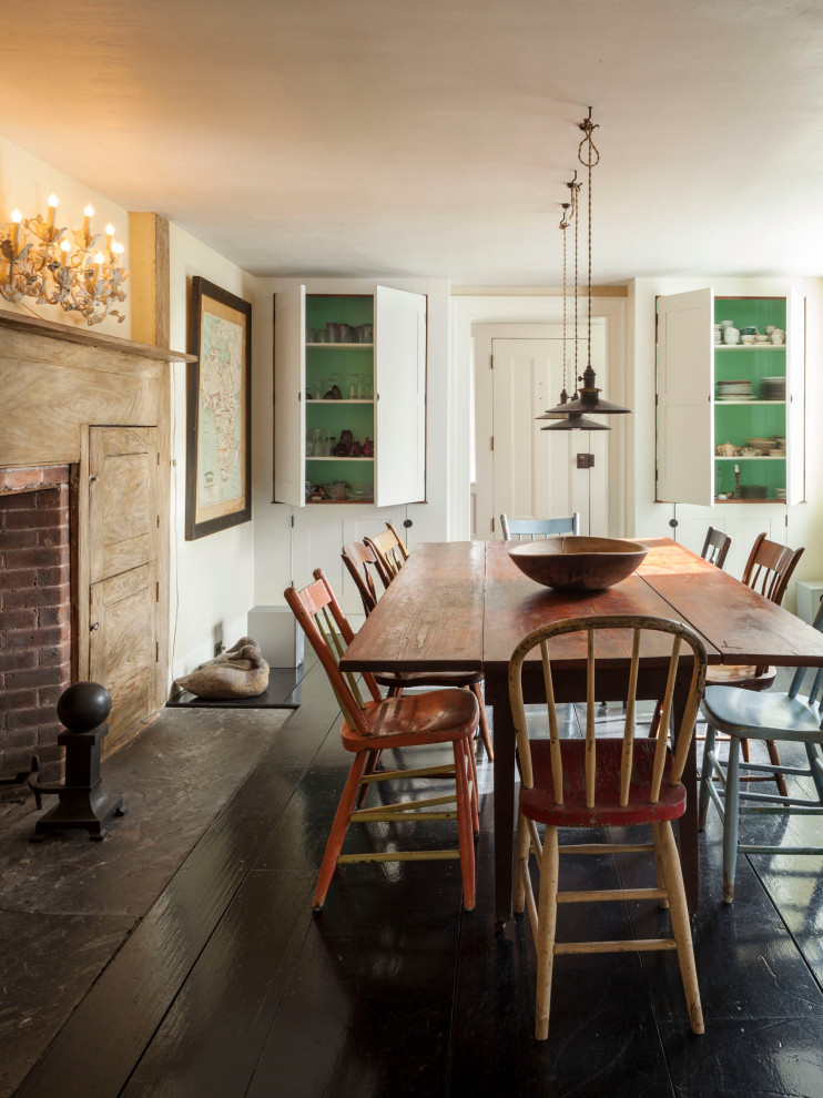 Photo of a country dining room in New York with white walls, dark hardwood flooring, a standard fireplace and brown floors.