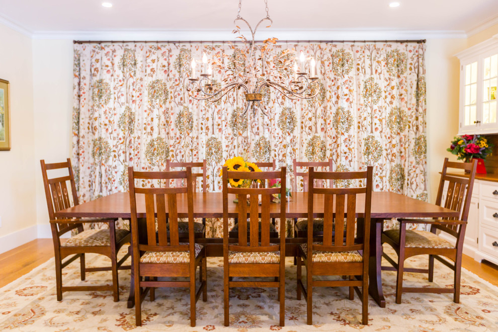 Immagine di una grande sala da pranzo aperta verso la cucina american style con pareti gialle e pavimento in legno massello medio