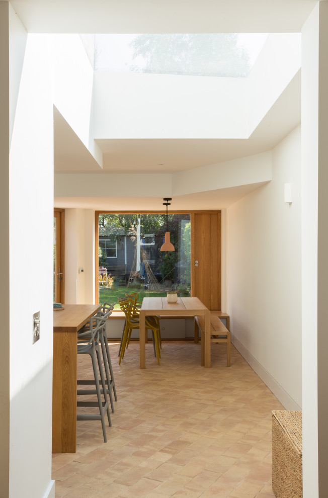 Kitchen/dining room combo - mid-sized contemporary terra-cotta tile and pink floor kitchen/dining room combo idea in Cambridgeshire with white walls
