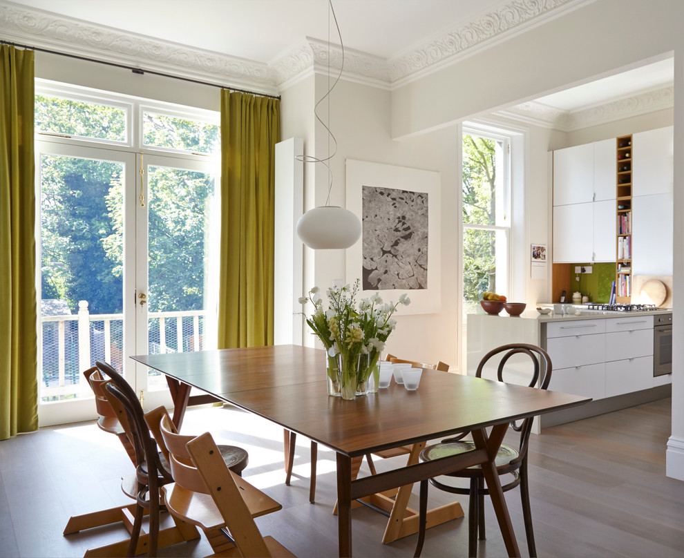 This is an example of a contemporary kitchen/dining room in London with white walls and medium hardwood flooring.