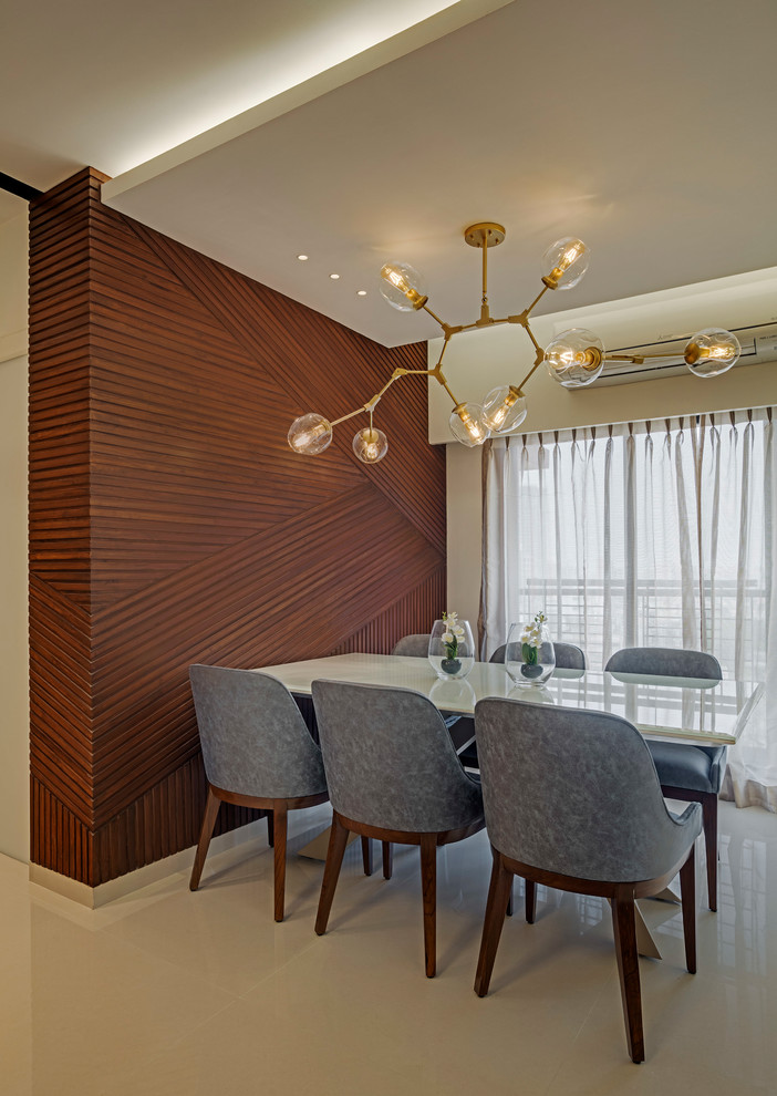 This is an example of a contemporary dining room in Mumbai with feature lighting.