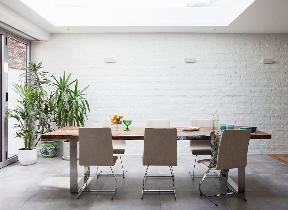 Ispirazione per una sala da pranzo aperta verso la cucina design di medie dimensioni con pareti bianche e pavimento in cemento