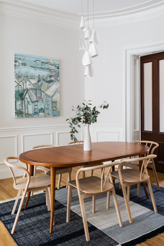 Ispirazione per una sala da pranzo contemporanea con pareti bianche, pavimento in legno massello medio, pavimento marrone e boiserie