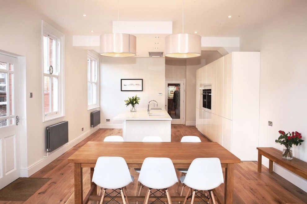 Foto di una sala da pranzo aperta verso la cucina design di medie dimensioni con pareti bianche e pavimento in legno massello medio