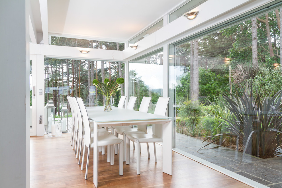This is an example of a contemporary dining room in Devon with white walls and medium hardwood flooring.