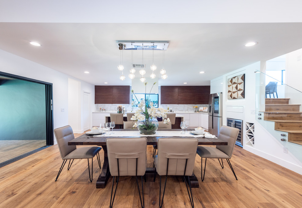 Große Moderne Wohnküche mit weißer Wandfarbe, hellem Holzboden, Eckkamin, Kaminumrandung aus Backstein und braunem Boden in Los Angeles