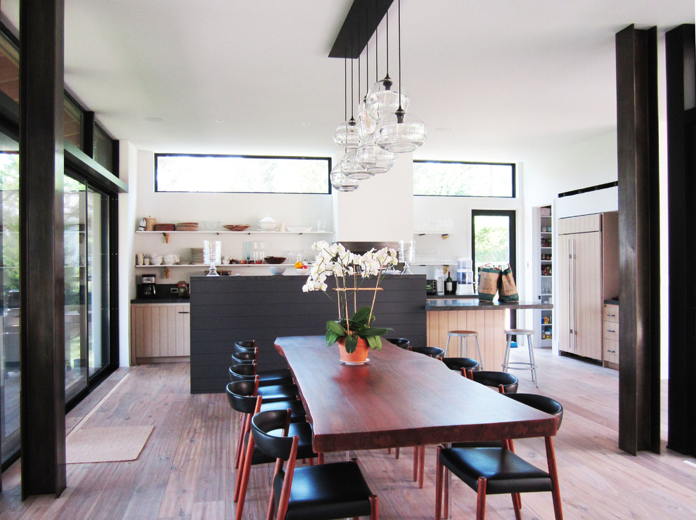 Aménagement d'une salle à manger ouverte sur la cuisine contemporaine avec un mur blanc et un sol en bois brun.