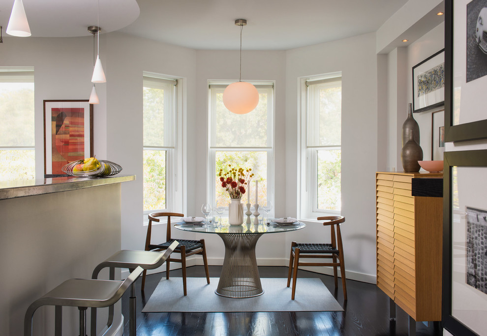 Cette photo montre une salle à manger ouverte sur la cuisine tendance avec un mur blanc et parquet foncé.