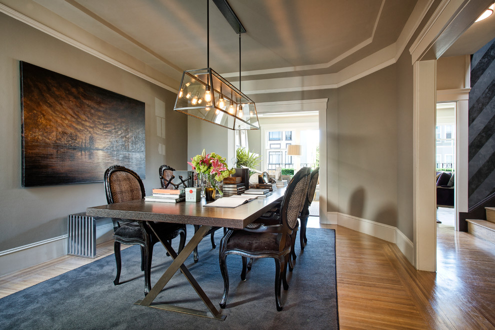 Cette photo montre une salle à manger tendance fermée avec un mur gris et un sol en bois brun.
