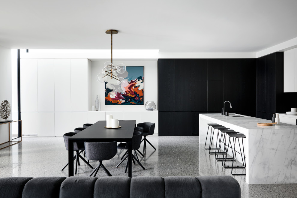 Cette image montre une salle à manger ouverte sur le salon design avec un mur blanc, sol en béton ciré et un sol gris.