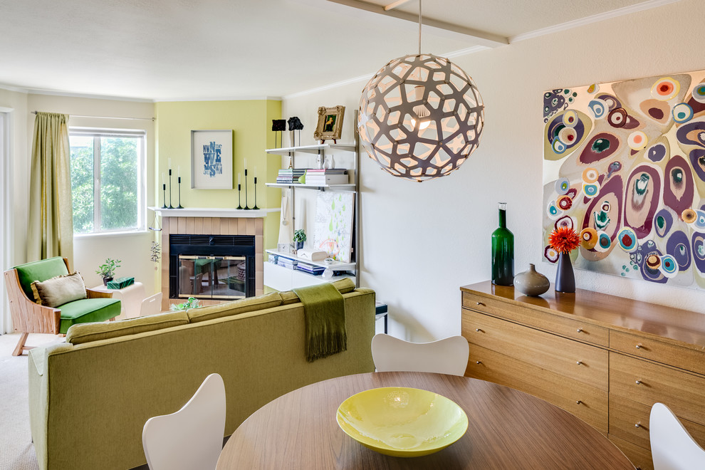 Cette image montre une petite salle à manger ouverte sur le salon design avec un mur blanc, moquette, un sol beige, une cheminée d'angle et un manteau de cheminée en carrelage.