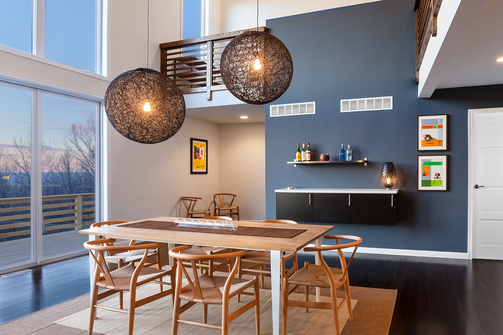 Réalisation d'une grande salle à manger ouverte sur le salon design avec un mur bleu, parquet foncé, un sol marron et aucune cheminée.