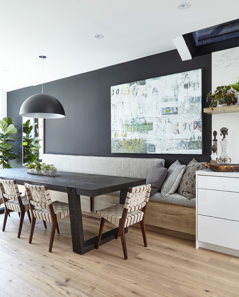 Cette image montre une grande salle à manger ouverte sur la cuisine design avec un mur noir, un sol beige et parquet clair.